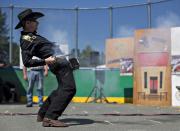 RNPS - PICTURES OF THE YEAR 2013 - Nick "The Quick" Nica of Montreal, Quebec, draws and fires his single action revolver while competing in the Canadian Open Fast Draw Championships in Aldergrove, British Columbia July 21, 2013. The present-day Fast Draw competition was born from the Hollywood myth of the Western gunfighter, and the idea is to draw a single action revolver from a holster, and cock, fire and hit a designated target in the shortest possible time. No live ammunition is ever used, only blank cartridges or wax bullets. The targets are either a metal silhouette used with wax bullets or balloons that burst from the muzzle blast from the blank cartridges. A light atop the timer signals the competitor when to fire and once the target is hit, it turns the timer off, measuring the speed to thousandths of a second. REUTERS/Andy Clark (CANADA - Tags: SPORT SOCIETY SHOOTING TPX)