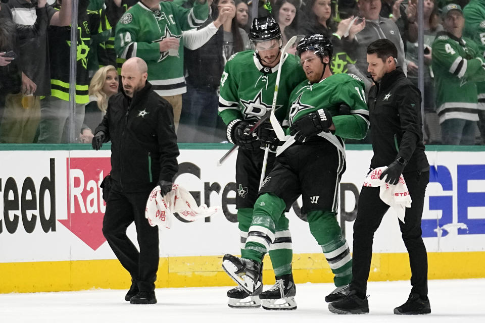 Dallas Stars' Joe Pavelski, second from right, is helped off the ice by Mason Marchment and staff after suffering an unknown injury in the second period of Game 1 of an NHL hockey Stanley Cup first-round playoff series against the Minnesota Wild, Monday, April 17, 2023, in Dallas. (AP Photo/Tony Gutierrez)