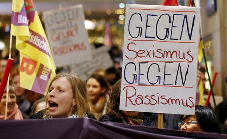 Women shout slogans and hold up a placard that reads "Against Sexism - Against Racism" as they march through the main railways station of Cologne, Germany, January 5, 2016. REUTERS/Wolfgang Rattay