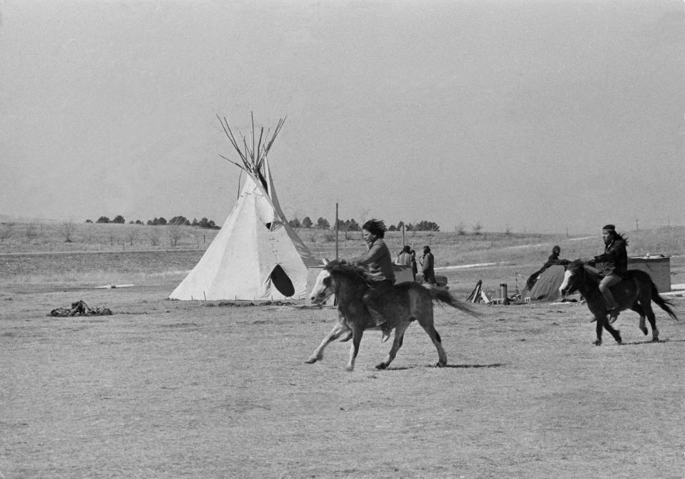 FILE - Native American youths on horses ride past a tipi at Wounded Knee, S.D., on March 21, 1973, as negotiations between the U.S. government and American Indian Movement leaders remain deadlocked. (AP Photo/Fred Jewell, File)