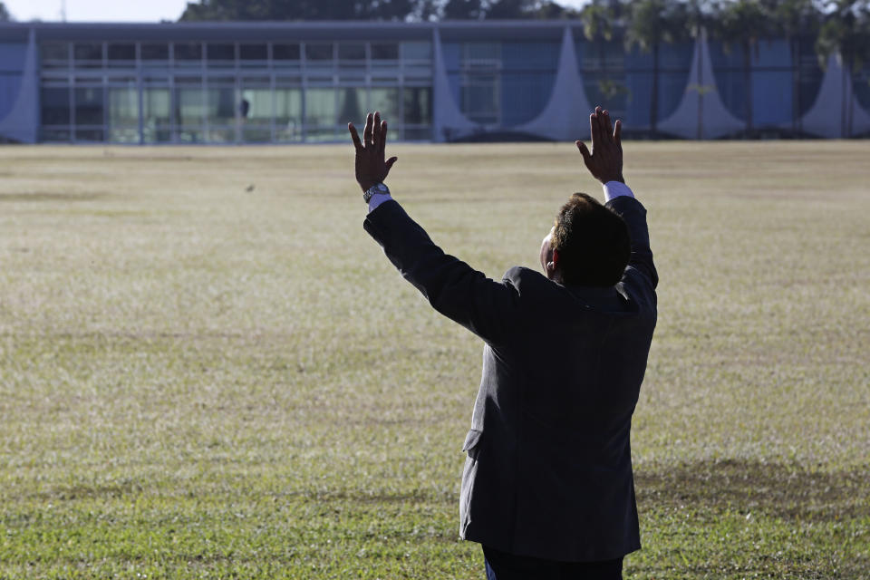 An evangelical pastor prays for Brazil's President Jair Bolsonaro, who said he tested positive for COVID-19, outside Alvorada Palace, the president's official residence in Brasilia, Brazil, Tuesday, July 7, 2020. (AP Photo/Eraldo Peres)