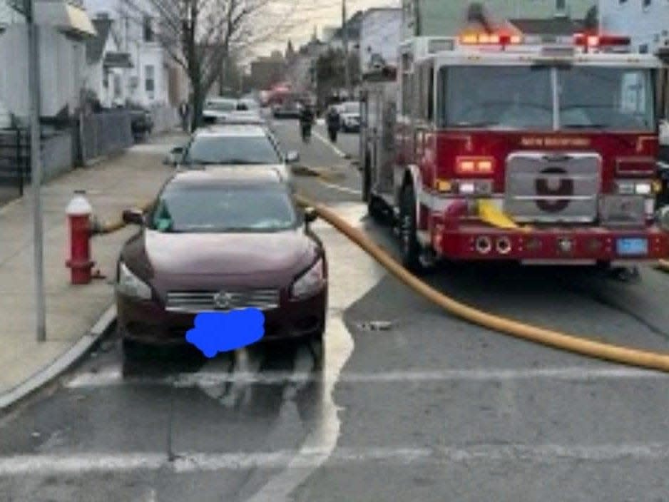 A photo showing firefighters had to break through the windows of a parked car to get the hose to a fire hydrant.