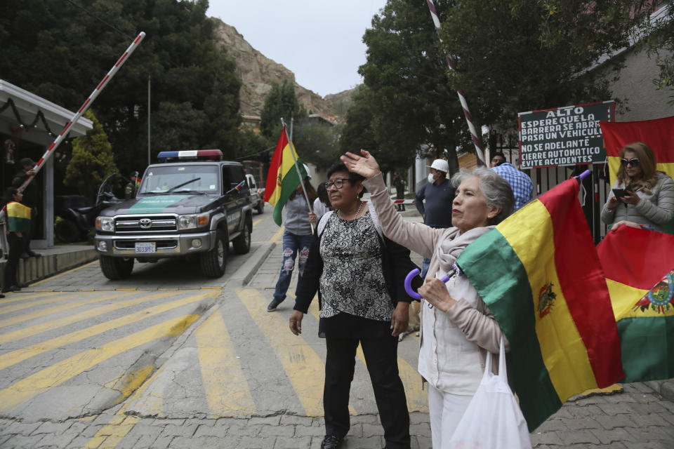 People protest at the entrance leading to the residence of Mexico’s ambassador to help make sure nine former officials from the government of deposed Bolivian President Evo Morales, who have taken refuge inside, do not leave the country, amid police presence in La Paz, Bolivia, Monday, Dec. 30, 2019. Bolivia’s interim government is expelling the top Mexican and Spanish diplomats in the country over an alleged attempt by members of Bolivia’s former government to leave refuge in the Mexican embassy with Spanish help and flee the country. (AP Photo/Luis Gandarillas)