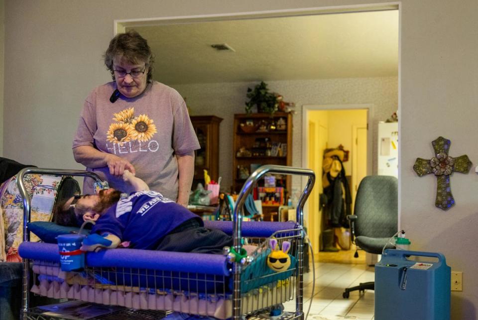 Debbie Wiederhold holds her son Daniel's hand in their home in Hutto on Feb. 29, 2024.