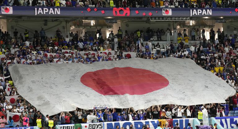 Los hinchas japoneses despliegan una bandera gigante en el comienzo del partido