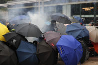 Protestors use umbrellas as shield as they face tear smoke from police in Hong Kong, Sunday, Sept. 29, 2019. Riot police fired tear gas Sunday after a large crowd of protesters at a Hong Kong shopping district ignored warnings to disperse in a second straight day of clashes, sparking fears of more violence ahead of China's National Day. (AP Photo/Vincent Thian)