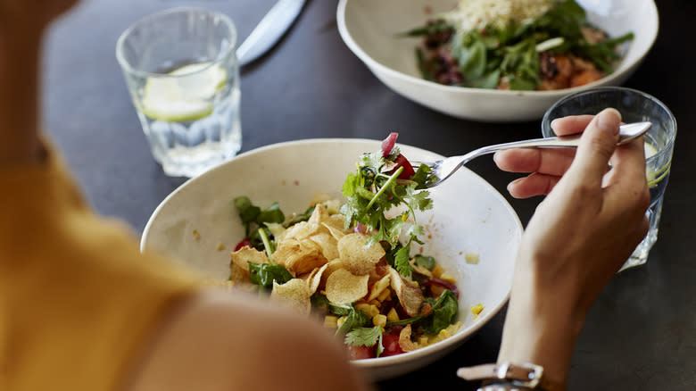 Close-up of a person's hand and plate dining at a restaurant