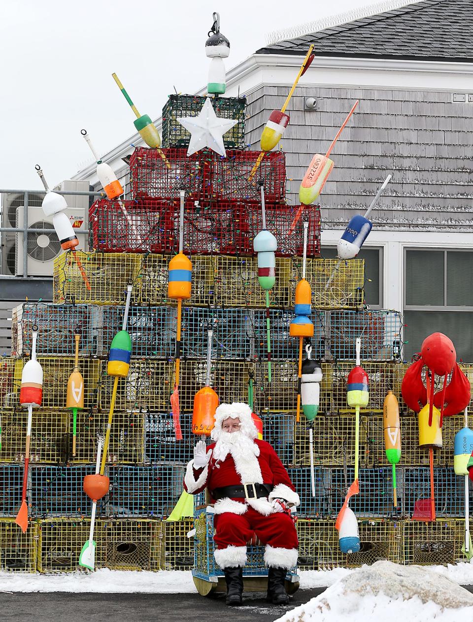 Santa waves to children while sitting at the foot of a giant lobster trap tree in Marshfield during the Santa at the Pier drive-thru event in 2020.