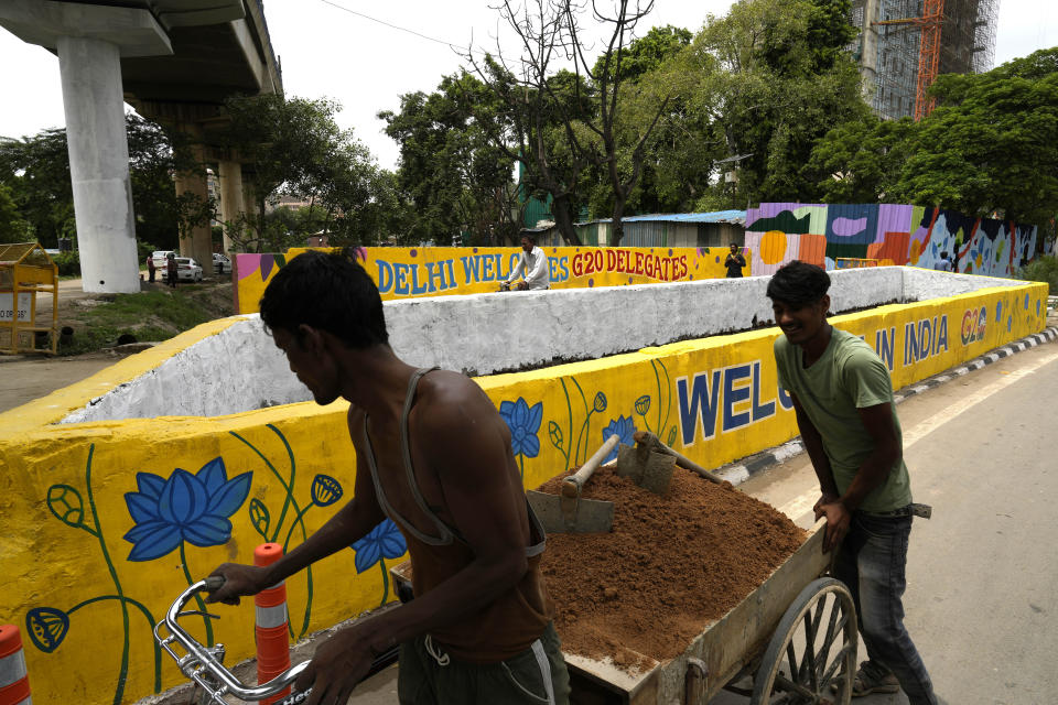 Labourers carry mud on a cycle cart for beautification of a street in New Delhi, India, Thursday, Aug. 24, 2023. As India gears up to host the annual gathering of the Group of 20 industrialized and developing nations, the capital city is undergoing an elaborate makeover. But for many street vendors and shantytowns dotting the city, the beautification of New Delhi has meant displacement and loss of livelihoods. (AP Photo/Manish Swarup)