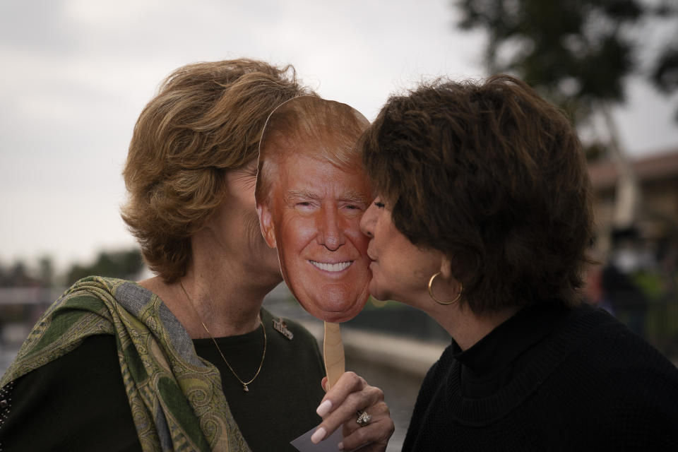 Shiela Ruiz, right, kisses a photo of President Donald Trump while mingling with Dale Thomas, president of Westlake Village Republican Women Federated, at a boat parade held in support of Trump in Westlake Village, Calif., Friday, Oct. 23, 2020. "Donald Trump! There is no question," Ruiz said when asked whom she was going to vote for. "Because he is the man who can lead the country in the way I want to see it led. I have waited for years for a non-politician to run for office." (AP Photo/Jae C. Hong)