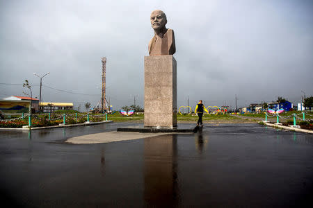 A woman walks past a statue of Soviet state founder Vladimir Lenin in Yuzhno-Kurilsk, the main settlement on the Southern Kuril island of Kunashir September 17, 2015. REUTERS/Thomas Peter/File Photo