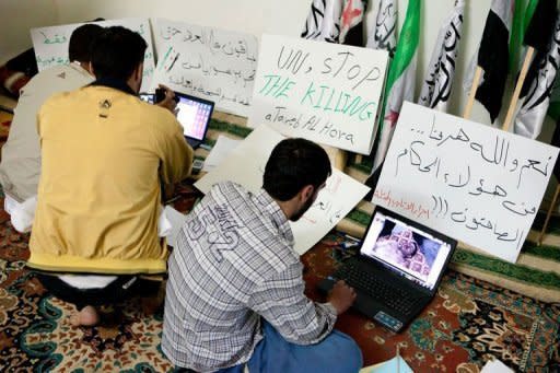 Syrian activists upload pictures and news of unrest to opposition websites as they sit in front of anti-regime posters in the town of Atareb. Twin blasts targeting security buildings killed more than 20 people in the northwest Syrian city of Idlib, a monitoring group said, as the chief UN monitor presses both sides to end more than 13 months of violence