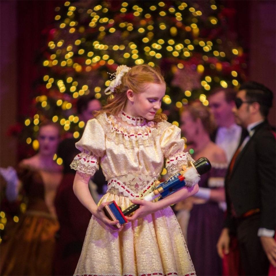 Clara gently cradles the nutcracker she got from Drosselmeyer during her parents' holiday party in this scene from Ballet Lubbock's annual production.