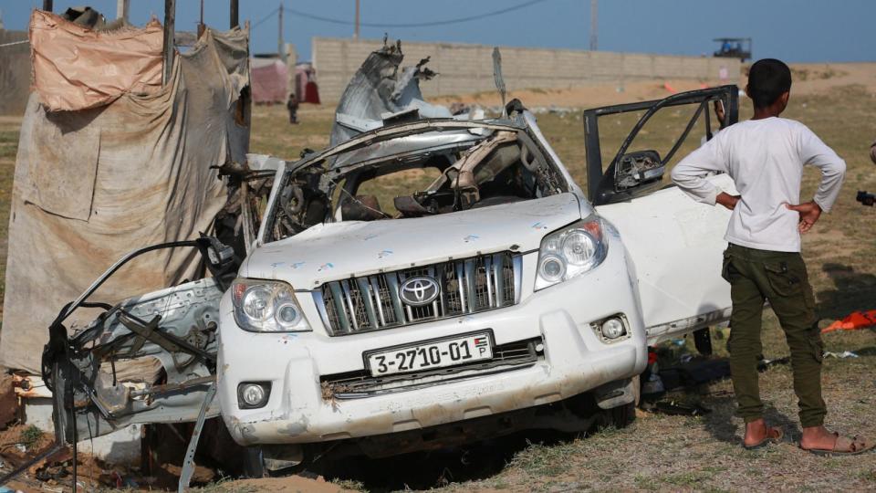 PHOTO: People gather around the carcass of a car used by US-based aid group World Central Kitchen, that was hit by an Israeli strike the previous day in Deir al-Balah in the central Gaza Strip on April 2, 2024. (AFP via Getty Images)