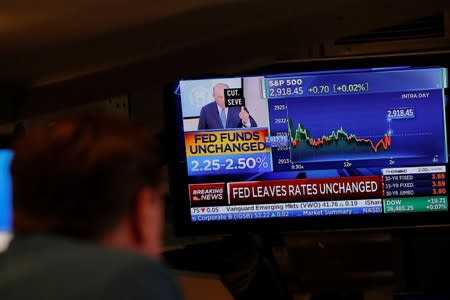 A trader looks at a screen as a television announces that the Fed rate will remain unchanged on the floor of the New York Stock Exchange in New York