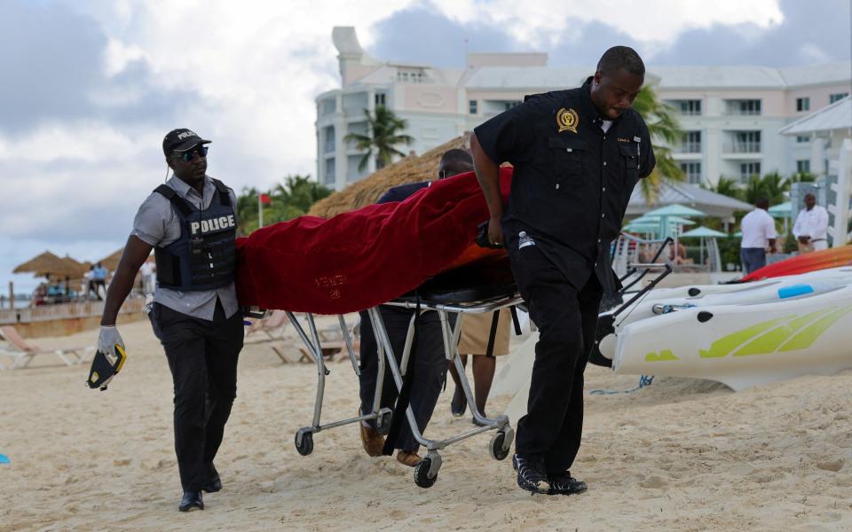 The body of Ms Van Wart is brought ashore by police mortuary personnel near the resort
