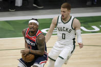 Washington Wizards' Bradley Beal, left, drives to the basket against Milwaukee Bucks' Donte DiVincenzo during the first half of an NBA basketball game Wednesday, May 5, 2021, in Milwaukee. (AP Photo/Aaron Gash)