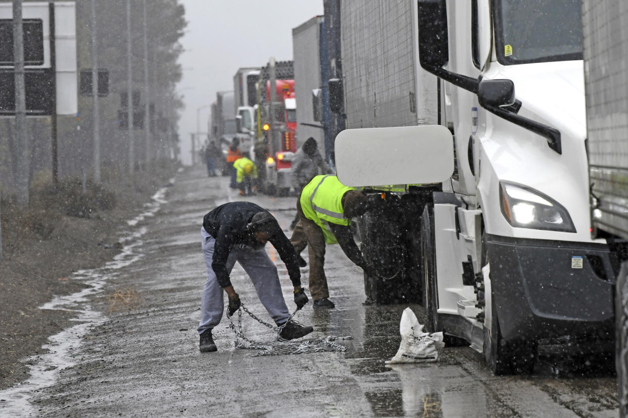 A long line of trucks are parked off the west bound I-80 as drivers put chains on the wheels.