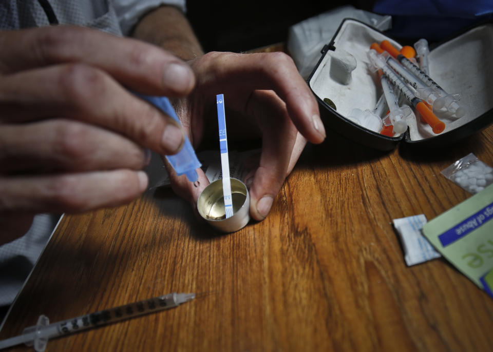 An addict prepares heroin, placing a fentanyl test strip into the mixing container to check for contamination, Wednesday Aug. 22, 2018, in New York. If the strip registers a "pinkish" to red marker then the heroin is positive for contaminants. (AP Photo/Bebeto Matthews)