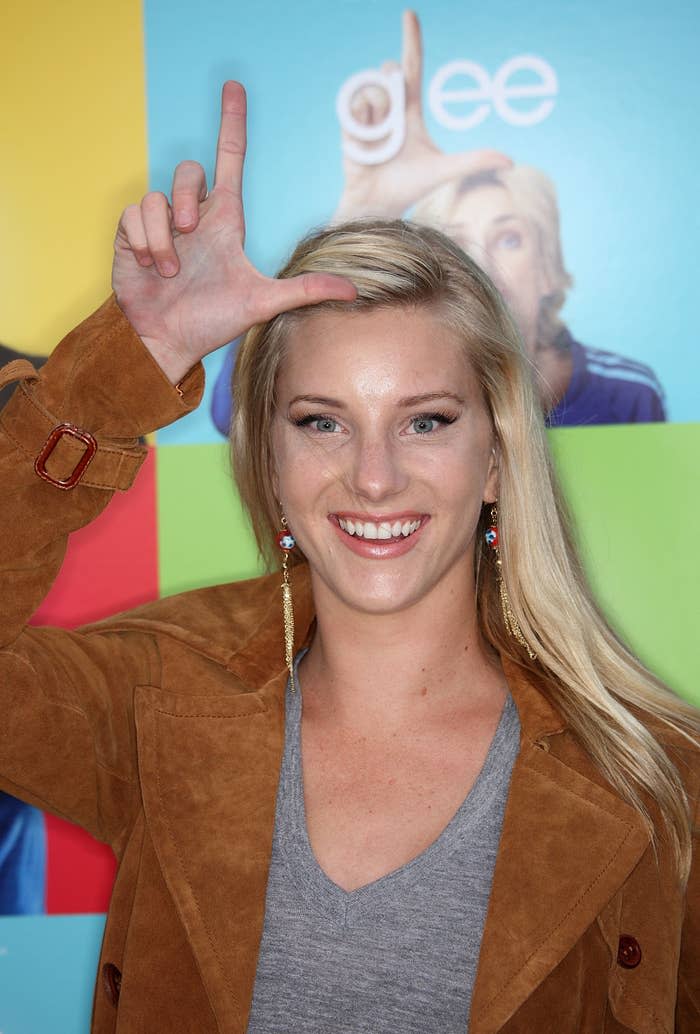 Heather smiles for a photo while holding up the letter L over her head