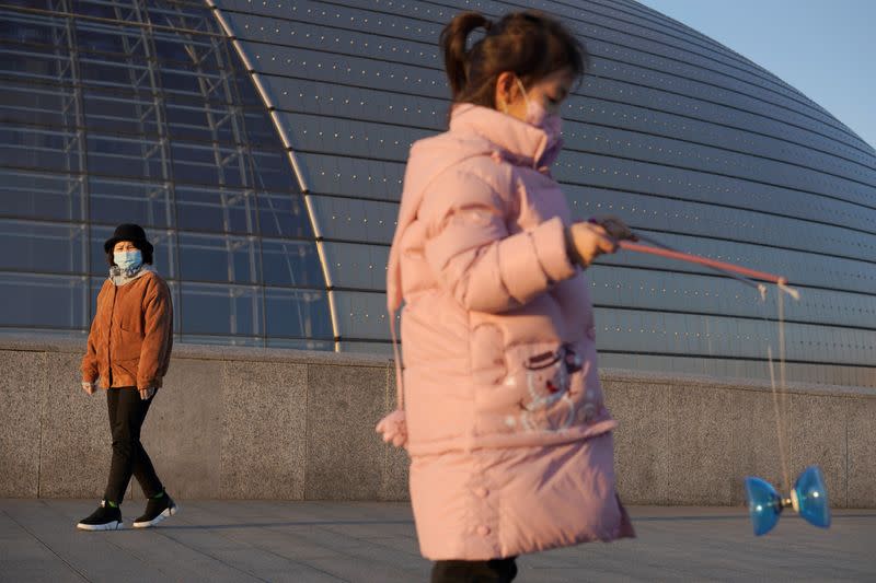 Girl wearing a face mask plays with a diabolo near the National Centre for the Performing Arts, following an outbreak of the novel coronavirus in the country, in Beijing