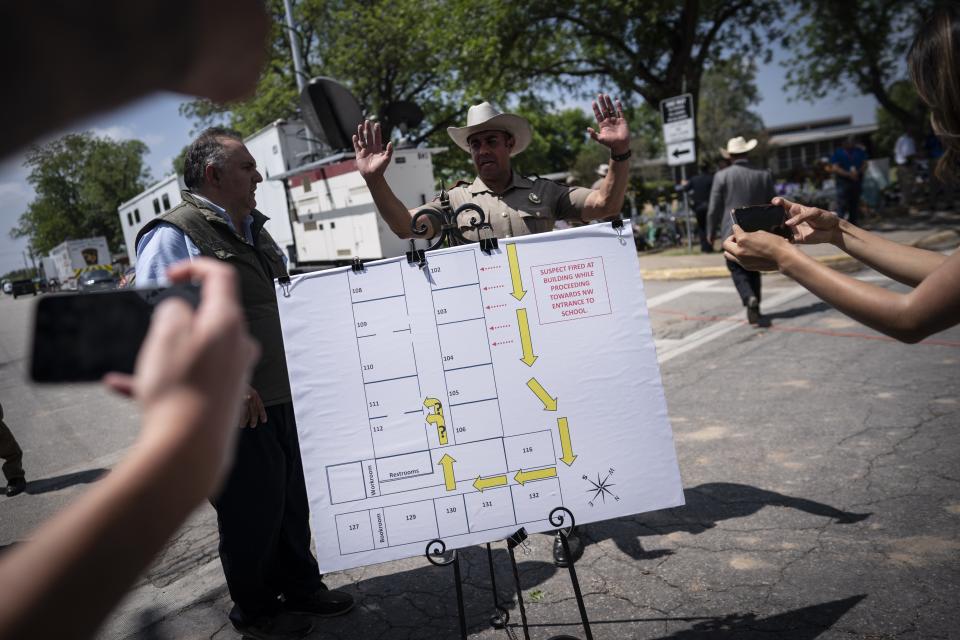 Members of the media take photos of a map of the school which was used a press conference held outside Robb Elementary School on Friday, May 27, 2022, in Uvalde, Texas. Nearly 20 officers stood in a hallway outside of the classrooms during this week's attack on a Texas elementary school for more than 45 minutes before agents used a master key to open a door and confront a gunman, authorities said Friday. (AP Photo/Wong Maye-E)