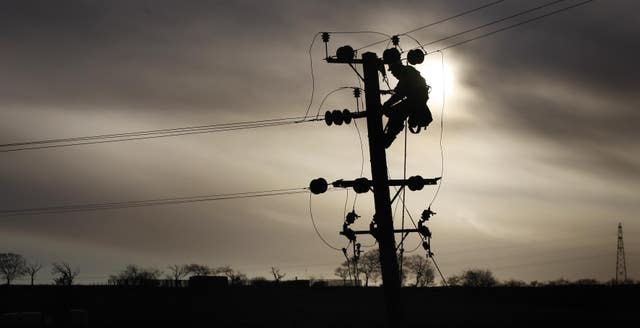 A linesman repairs an overhead line to restore electricity to Shieldhill, Scotland