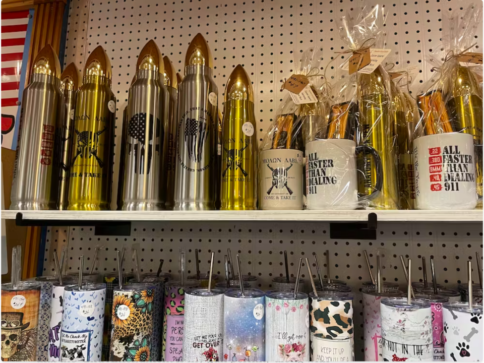 A shelf of bullet-themed coffee mugs and gift items for sale.