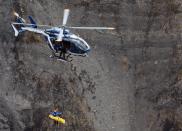 A French gendarmerie helicopter winches up an investigator on March 26, 2015 near scattered debris on the crash site of the Germanwings Airbus A320 in the French Alps above the southeastern town of Seyne