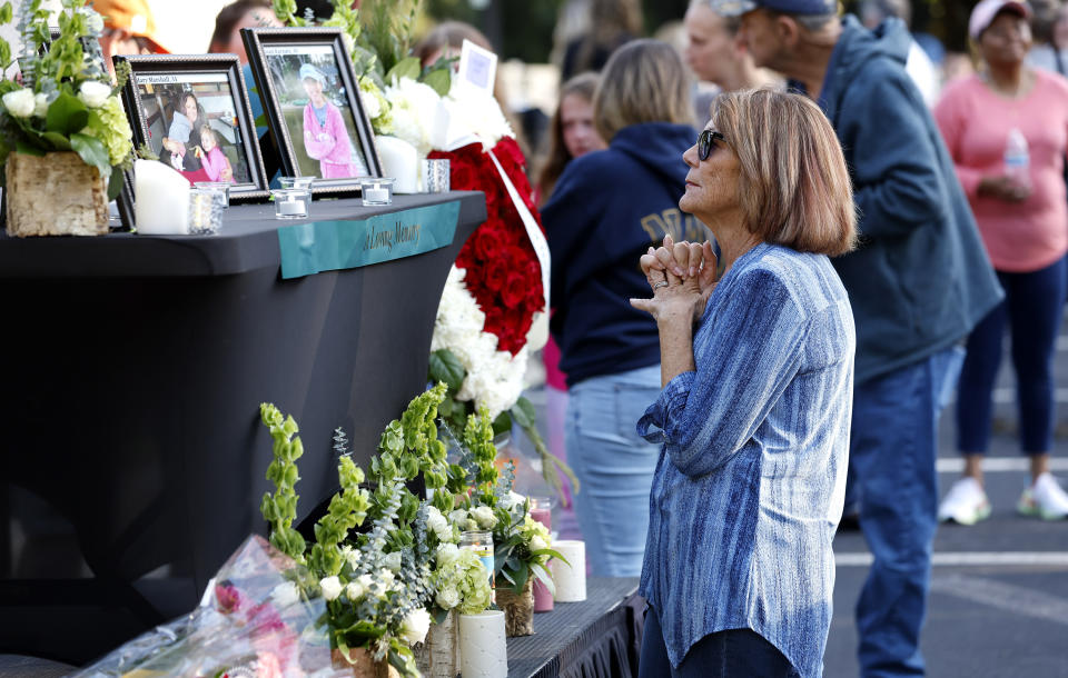 After a candlelight vigil outside the Hedingham clubhouse Saturday, Oct. 15, 2022, attendees look at a memorial for those killed and wounded in a Thursdays mass shooting in the Hedingham neighborhood in Raleigh, N.C. (Ethan Hyman/The News & Observer via AP)