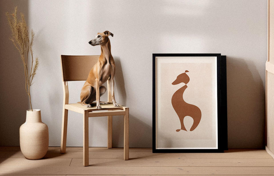 A brown greyhound sits in front of a poster of a brown greyhound