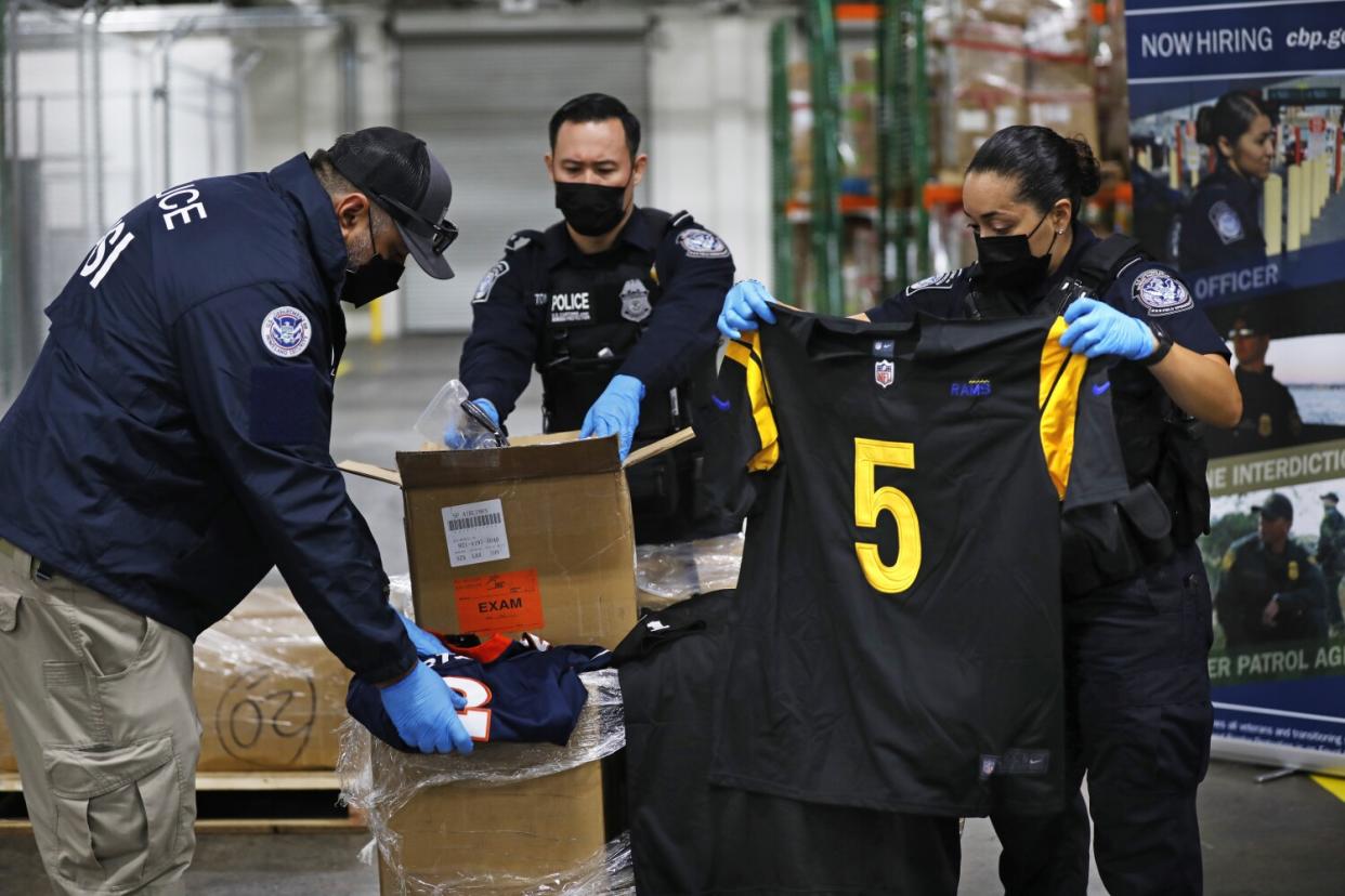 U.S. Customs and Border Protection officers open boxes of counterfeit goods
