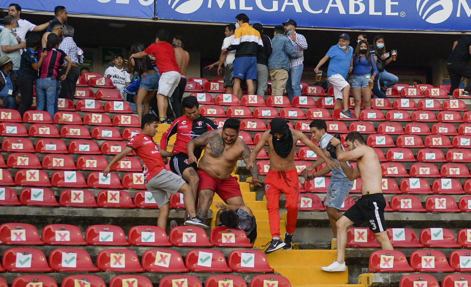 Fans clash during a Mexican soccer league match between the host Queretaro and Atlas from Guadalajara, at the Corregidora stadium, in Queretaro, Mexico, Saturday, March 5, 2022. Multiple people were injured during the brawl, including two critically. (AP Photo/Sergio Gonzalez)