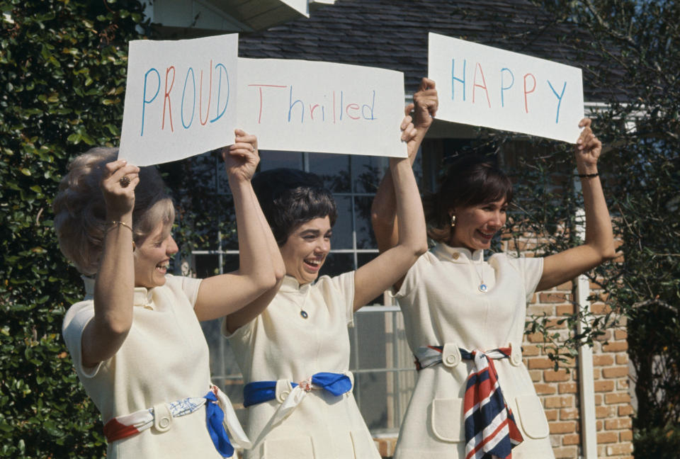 (Original Caption) Nassau Bay, Texas: Wearing identical pantsuits and carrying signs reading, Proud, Thrilled, Happy, the wives of the three Apollo 12 crewmen meet the press following successful return to the command module in lunar orbit of the lunar lander. Left to right: Mrs. Alan (Sue ) Bean, Mrs. Richard (Barbara) Gordon, and Mrs. Charles (Jane) Conrad. They carried the signs to answer newsmen's questions as to how they felt about the mission.