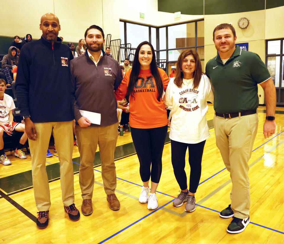From left, Oliver Ames head coach Oliver Vil, Michael Byron (son), Jennifer Byron (daughter), Christine Byron (wife), and Abington head coach Peter Serino, presented the family a check for the Don Byron scholarship fund and Coaches versus Cancer before his memorial game between Oliver Ames versus Abington on Wednesday, Feb. 15, 2023. 