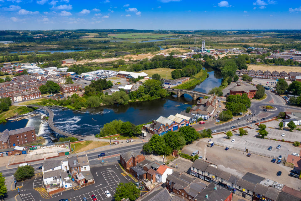 Aerial photo of the village centre of Castleford in Wakefield, West Yorkshire, England showing the main street along side the River Aire on a bright sunny summers day