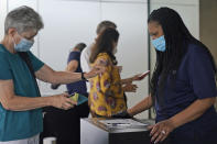 FILE - In this Sept. 13, 2021, staff at the Modern Museum of Art check visitors' proof of vaccination in New York. In both the U.S. and the EU, officials are struggling with the same question: how to boost vaccination rates to the max and end a pandemic that has repeatedly thwarted efforts to control it. In the United States, President Joe Biden has issued sweeping vaccine mandates. (AP Photo/Seth Wenig, File)