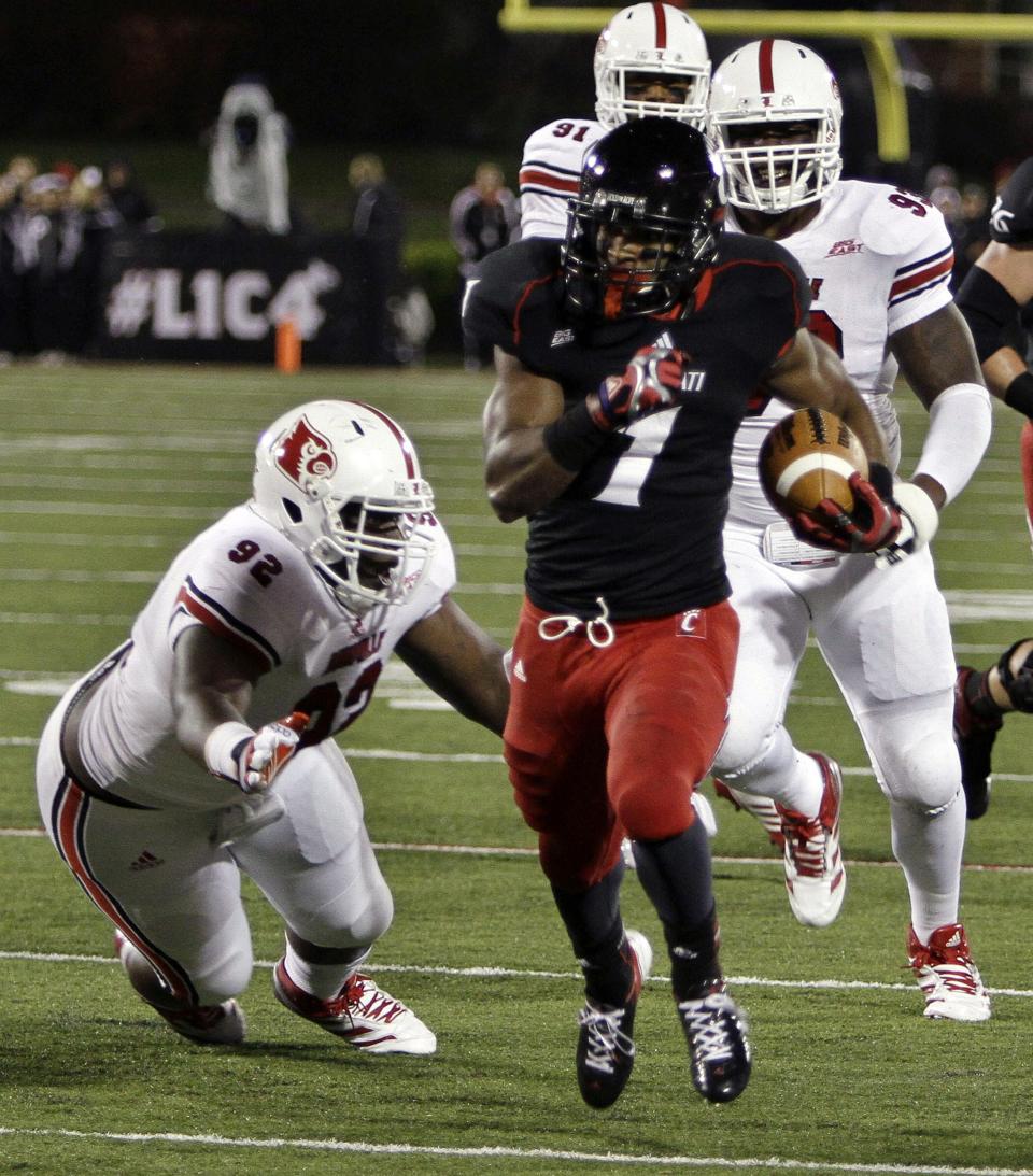 Cincinnati running back Ralph David Abernathy (1) sprints away from Louisville's Brandon Dunn (92) and Roy Philon (93) to score on a 14-yard run during the first quarter of an NCAA college football game in Louisville, Ky., Friday, Oct. 26, 2012.