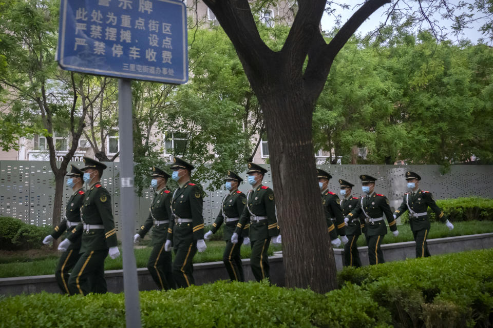 Chinese paramilitary police wearing face masks march in formation along a street in the embassy district in Beijing, Wednesday, April 27, 2022. China's capital city Beijing is in the middle of mass testing millions of residents after cases were discovered over the weekend. The city reported over 30 new cases Wednesday, several of which were asymptomatic. (AP Photo/Mark Schiefelbein)