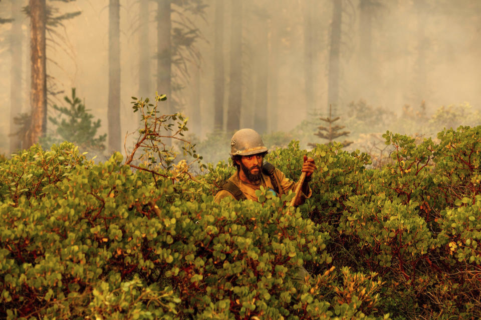 Firefighter Cody Carter battles the North Complex Fire in Plumas National Forest, Calif., on Monday, Sept. 14, 2020. Firefighters trying to contain the massive wildfires in Oregon, California and Washington state are constantly on the verge of exhaustion as they try to save suburban houses, including some in their own neighborhoods. (AP Photo/Noah Berger)