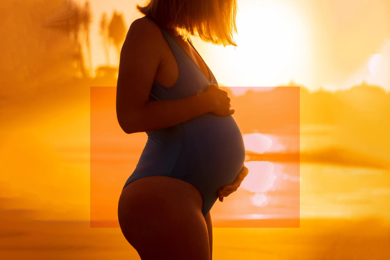 Profile of a pregnant woman in a one-piece bathing suit with a bright, sunny beach background