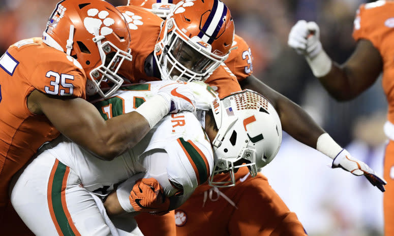 Clemson football players tackle a Miami Hurricane during the ACC Championship college football game.