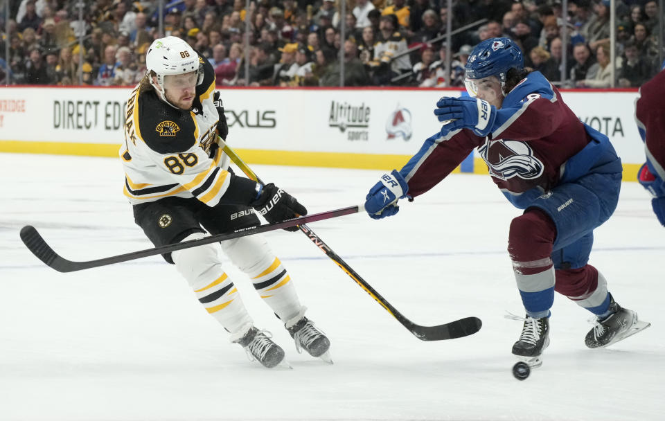 Boston Bruins right wing David Pastrnak, left, fires a shot past Colorado Avalanche defenseman Samuel Girard in the second period of an NHL hockey game, Wednesday, Dec. 7, 2022, in Denver. (AP Photo/David Zalubowski)