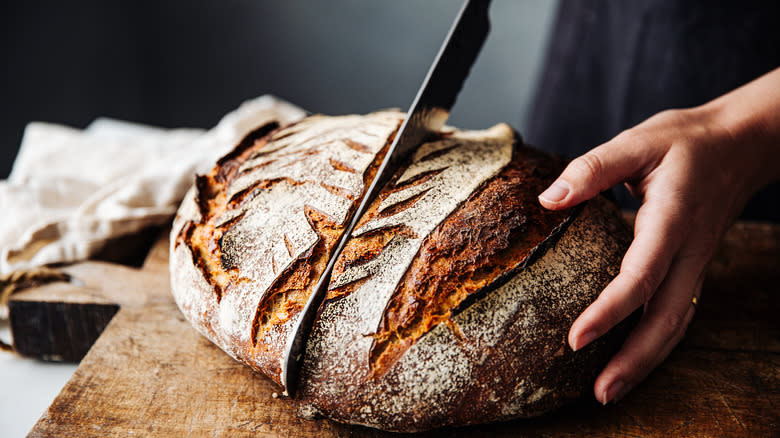 Person cutting into sourdough bread