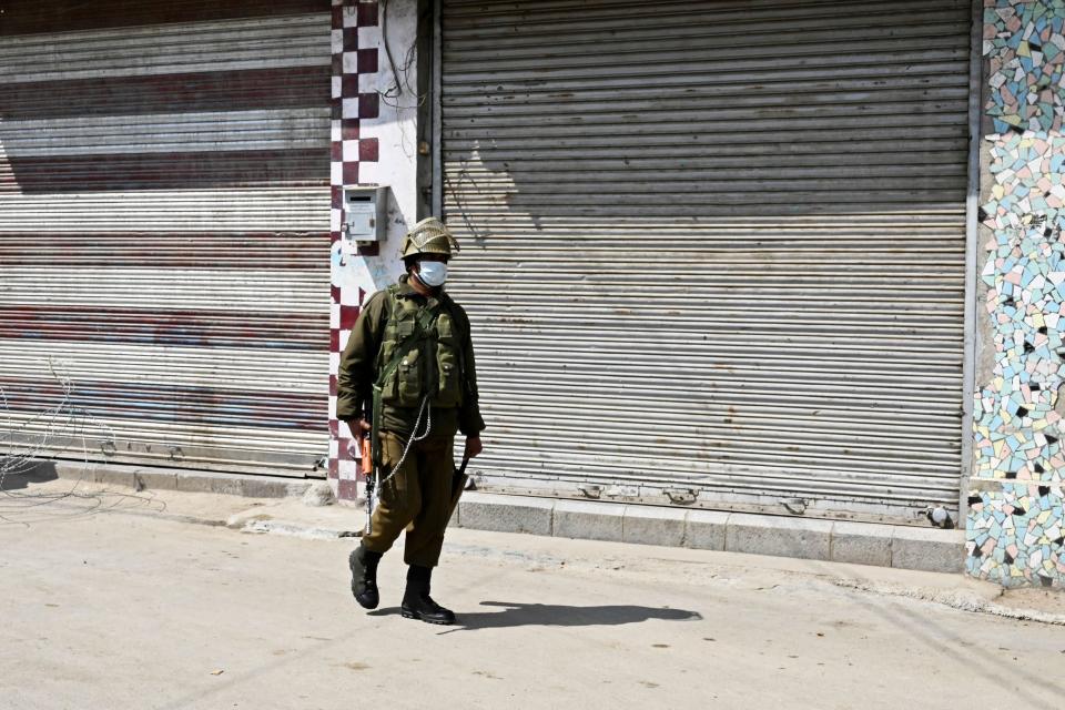 A security personnel wearing a facemask stands guard along a deserted street during a one-day nationwide Janata (civil) curfew imposed as a preventive measure against the COVID-19 coronavirus, in Srinagar on March 22, 2020. - Nearly one billion people around the world were confined to their homes, as the coronavirus death toll crossed 13,000 and factories were shut in worst-hit Italy after another single-day fatalities record. (Photo by Tauseef MUSTAFA / AFP) (Photo by TAUSEEF MUSTAFA/AFP via Getty Images)