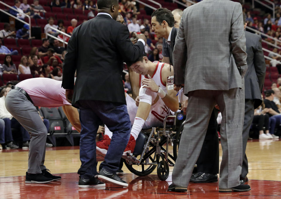 Houston Rockets forward Zhou Qi (9) is taken from the court in a wheelchair after injuring his left knee on a loose ball scramble play with Shanghai Sharks forward Luis Scola (4) during the first half of an exhibition NBA basketball game Tuesday, Oct. 9, 2018, in Houston. (AP Photo/Michael Wyke)
