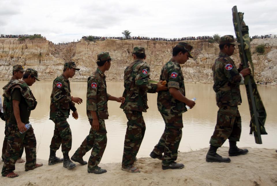 Cambodia's soldiers walk at the site where a Cambodian military helicopter crashed on the outskirts of Phnom Penh July 14, 2014. The military helicopter crashed on Monday, killing five and injured one, police told Reuters. A Cambodian air force official said authorities are still investigating the cause of the crash. (REUTERS/Samrang Pring)