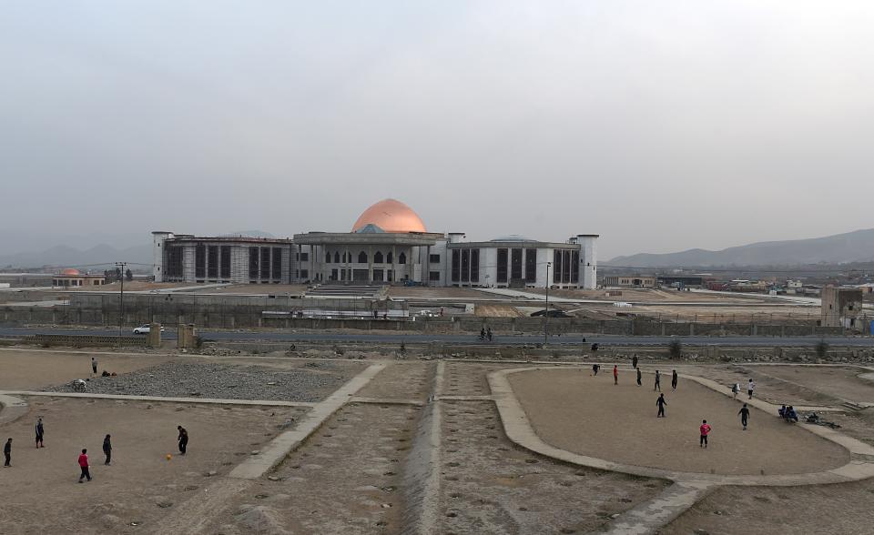 Afghan men play football as construction takes place of a new Parliament building in Kabul on February 10, 2015. AFP PHOTO/ SHAH Marai        (Photo credit should read SHAH MARAI/AFP via Getty Images)