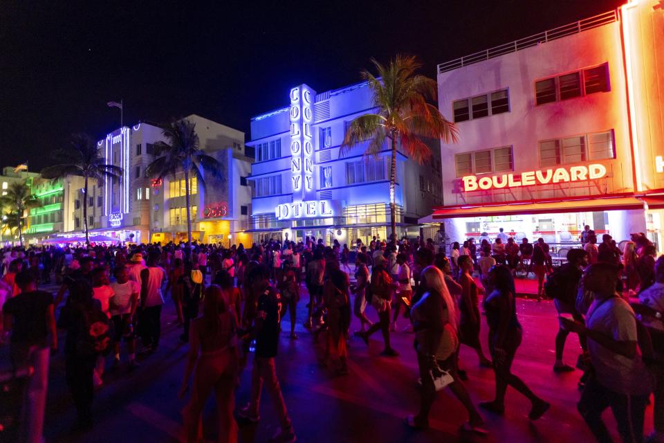 Crowds walk up and down Ocean Drive during spring break on Saturday, March 18, 2023, in Miami Beach, Fla. Miami Beach officials imposed a curfew beginning Sunday night, March 19, after two fatal shootings and rowdy, chaotic crowds that police have had difficulty controlling. (D.A. Varela/Miami Herald via AP)