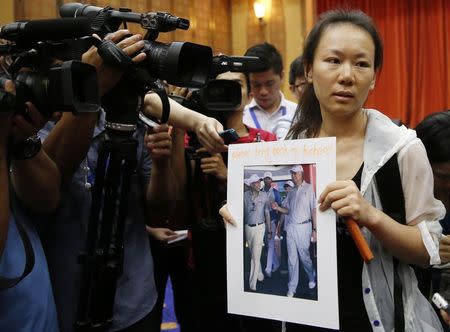 Kelly (last name not given), 29, the wife of a passenger aboard the missing Malaysia Airlines Flight MH370, holds a picture of her husband walking with Malaysia's Prime Minister Najib Razak, at a news conference in Putrajaya January 29, 2015. Malaysia declared on Thursday the disappearance of Malaysia Airlines Flight MH370 an accident, clearing the way for the airline to pay compensation to victims' relatives while the search for the plane goes on. REUTERS/Olivia Harris